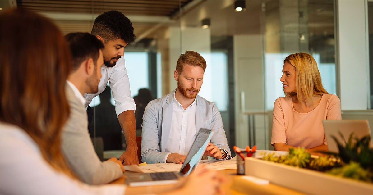 Five people sitting around a wooden conference table