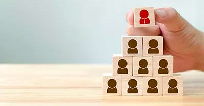 Hand stacking wooden blocks that have a person icon on them