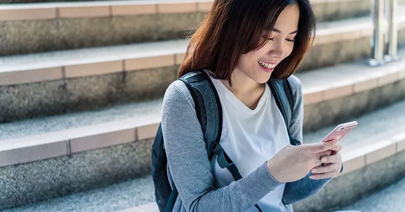 Woman smiling while reading her smartphone