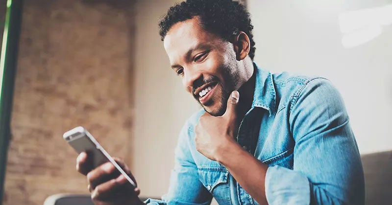 Man smiling while reading his smartphone