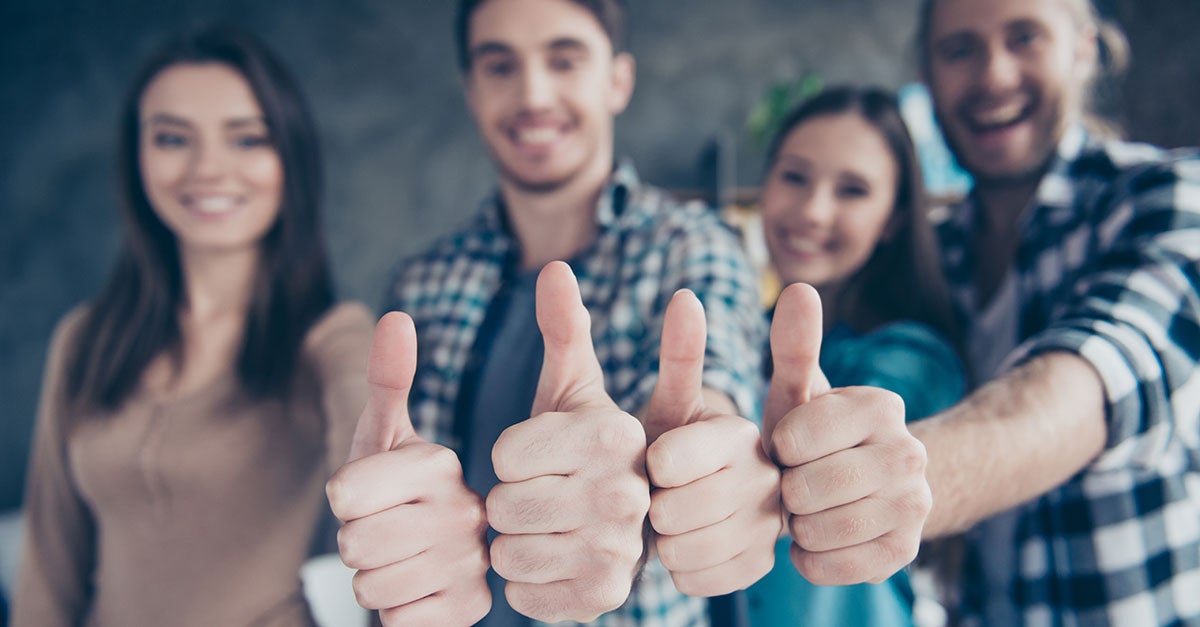 Four people all giving a thumbs up hand sign