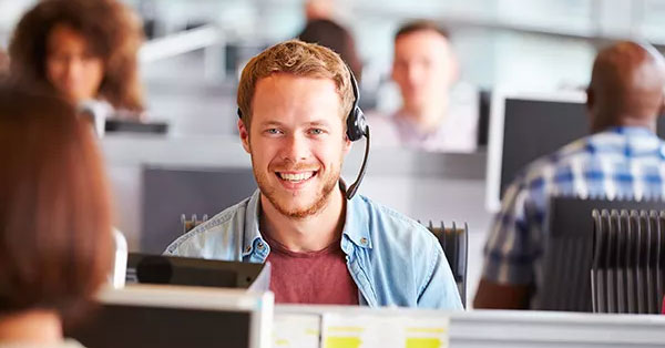 Man wearing a headset smiling into his computer monitor