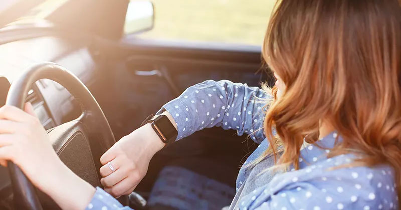 Woman driving and looking at watch