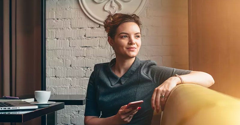 Woman sitting on a sofa in a coffee shop with her smartphone