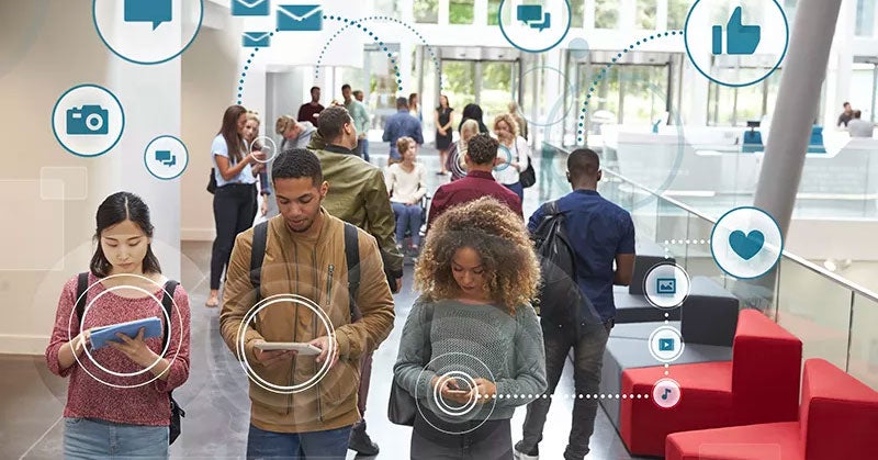 Crowd of people holding tablets and smartphones with computer icon overlay