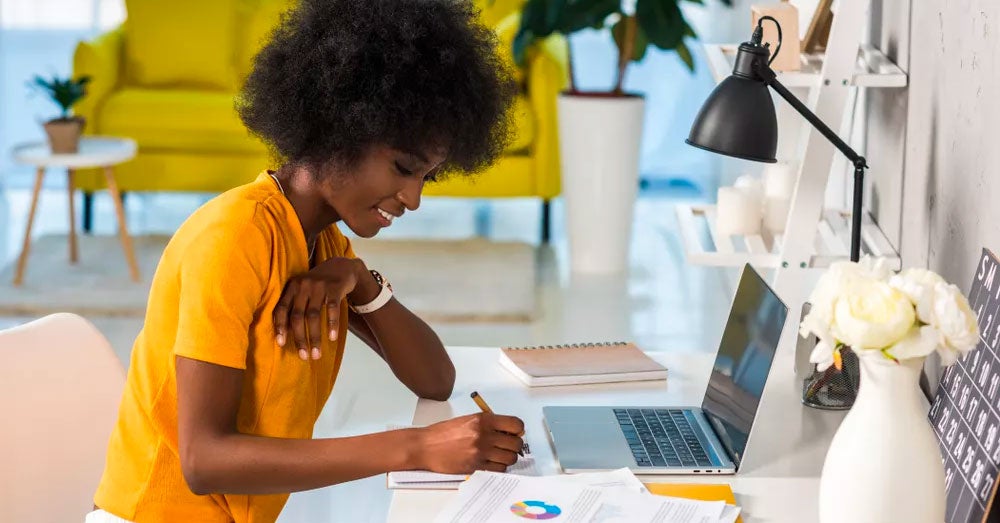 Woman taking notes while sitting at a laptop