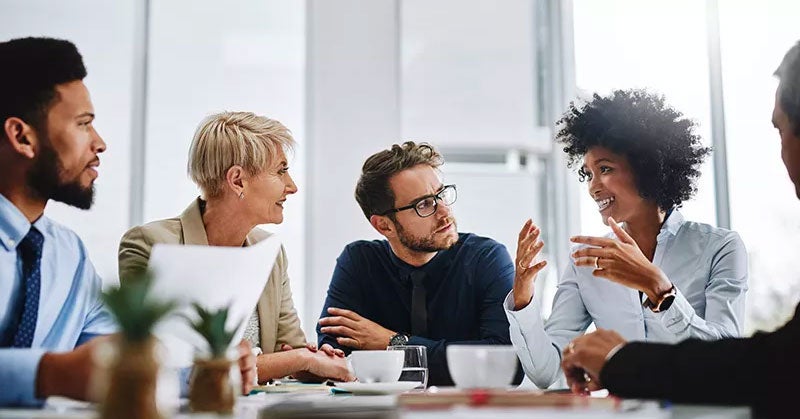 People in suits listening to a woman talking