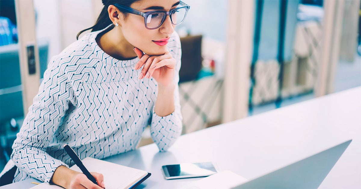 Women resting her chin on her hand while taking notes