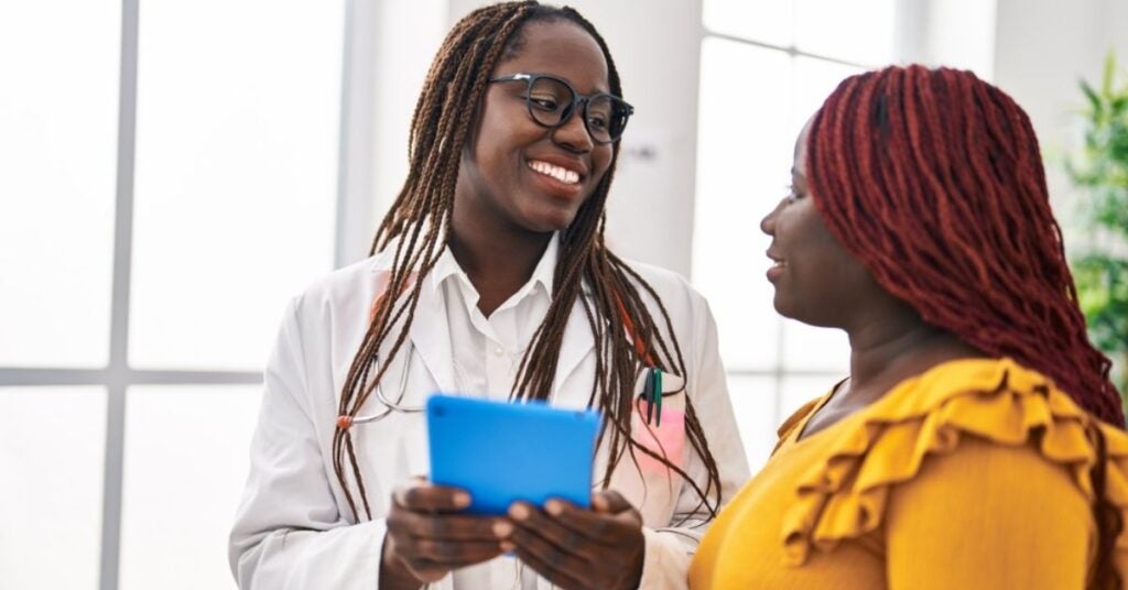 Medical professional holding a tablet while talking to a patient