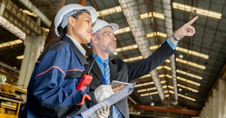 Two people in hardhats inside a factory