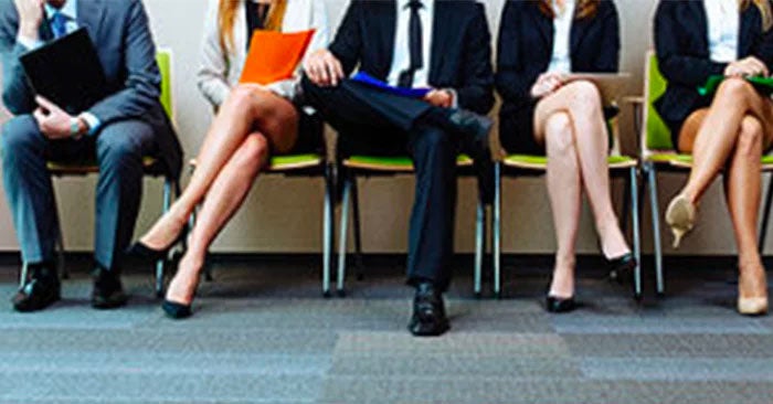 Row of people in suits sitting on green chairs