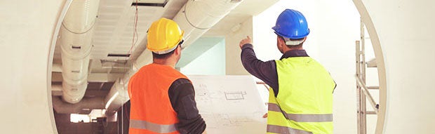 Two construction workers wearing hardhats and reflective vests