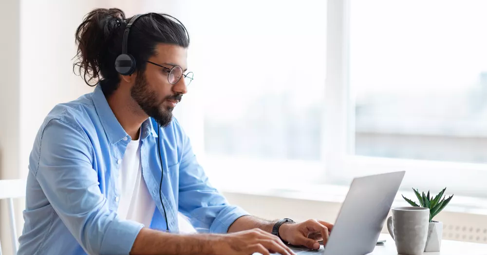 Man wearing headphones looking at a laptop screen