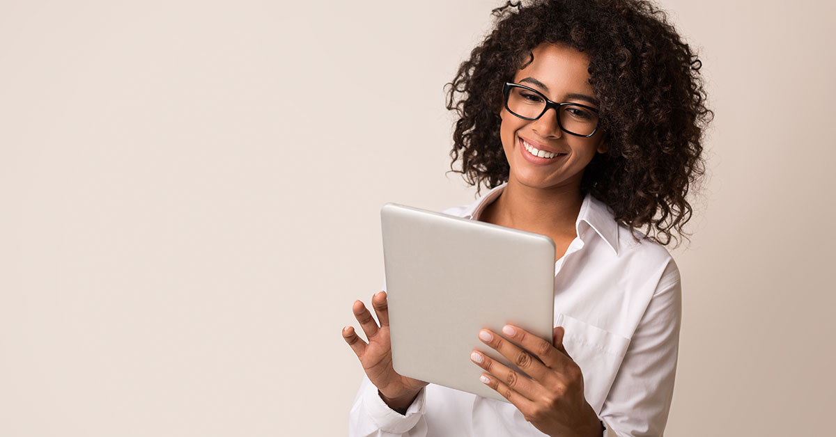 Woman scrolling on a tablet in front of a beige background