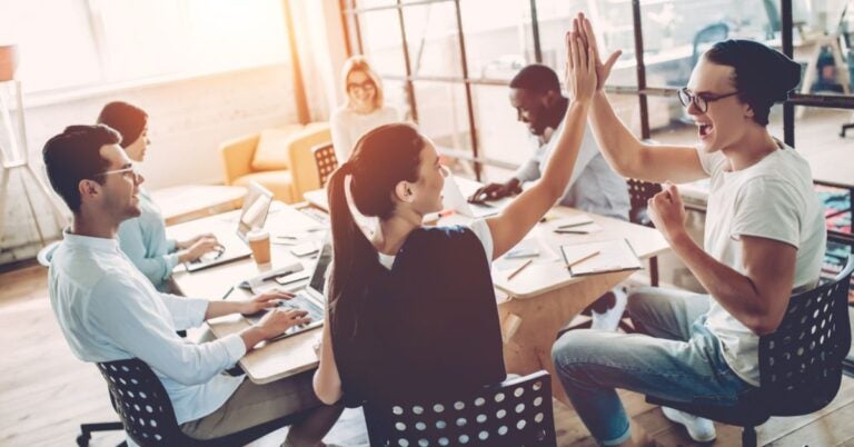 Two people giving each other a high five in a meeting