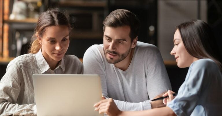 Three people looking at a laptop