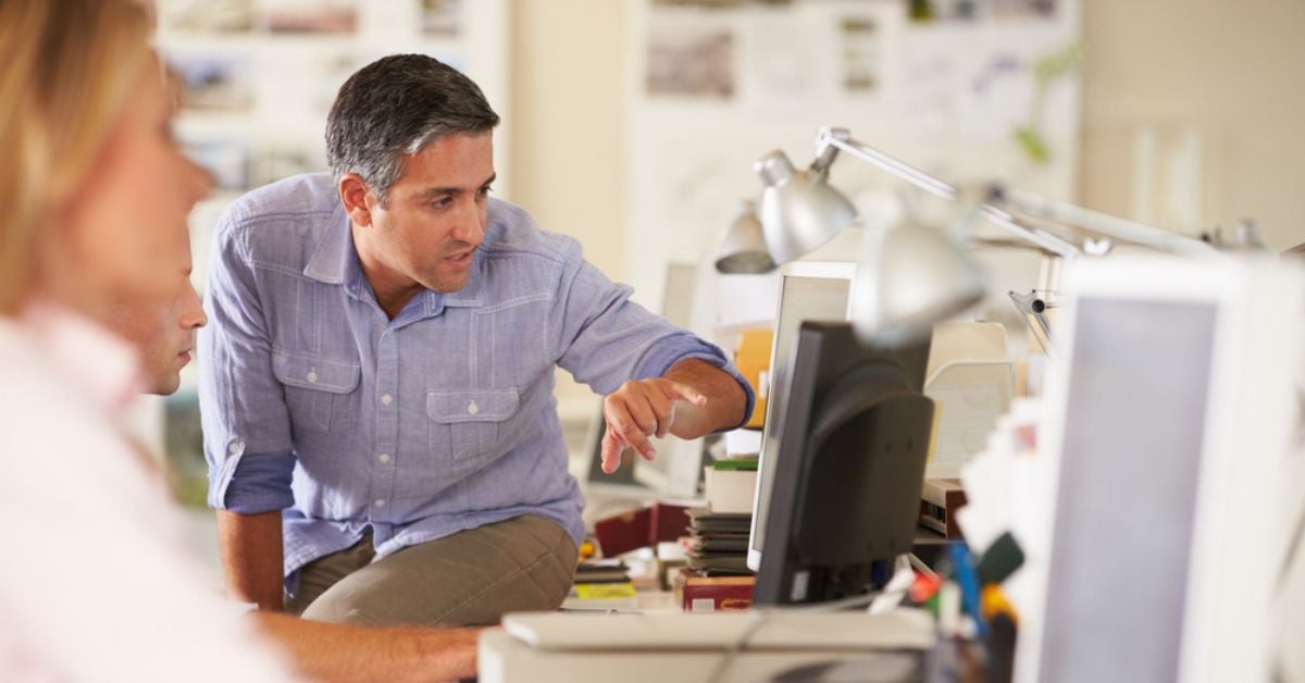 Man pointing towards a computer monitor and reading the screen