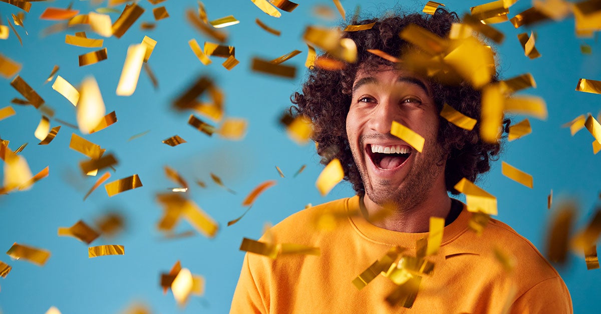 Man in yellow sweatshirt standing under gold confetti