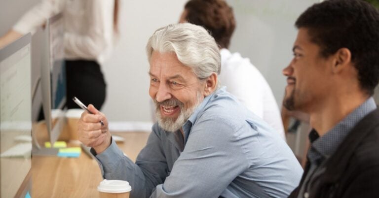 Man holding a pen while talking to another person