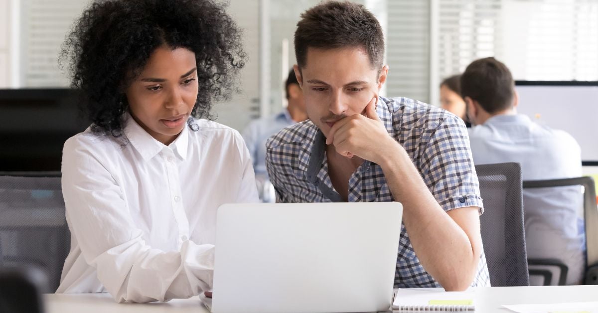 Two people reading a report on a laptop