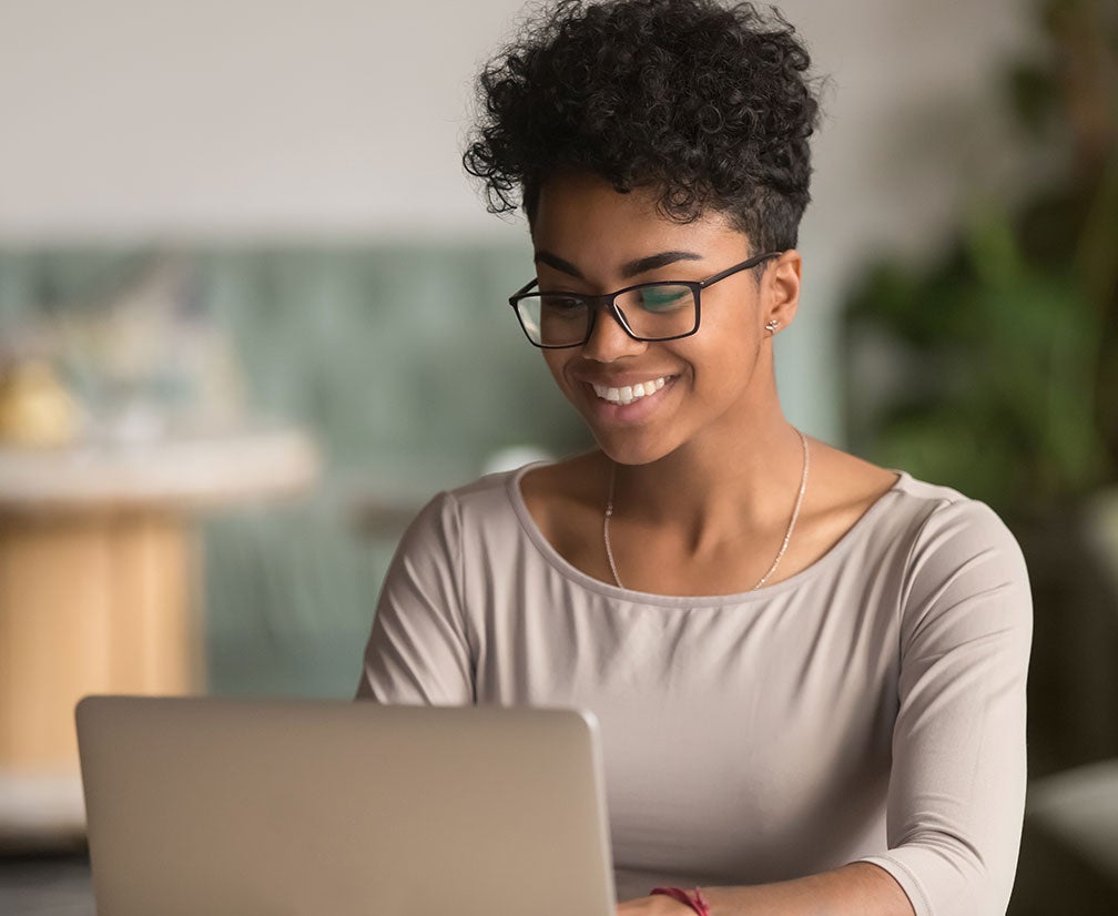 A woman smiling at a laptop computer