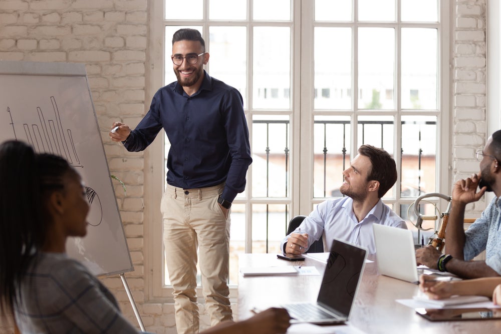 Young professional presenting information to a group of happy coworkers