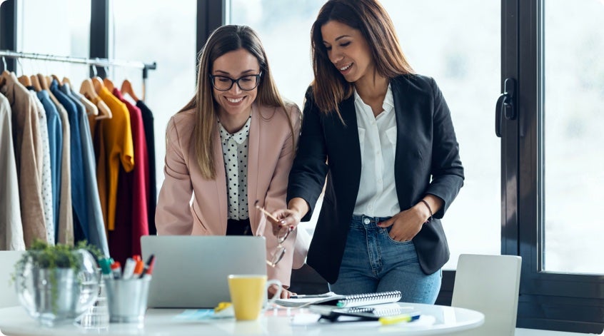 Two women in a clothing store looking at a laptop