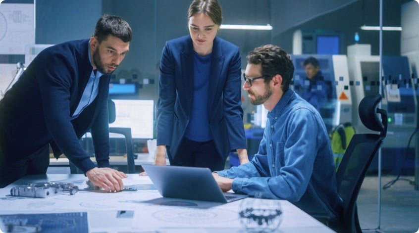 Three people gathered around a table in a glass conference room