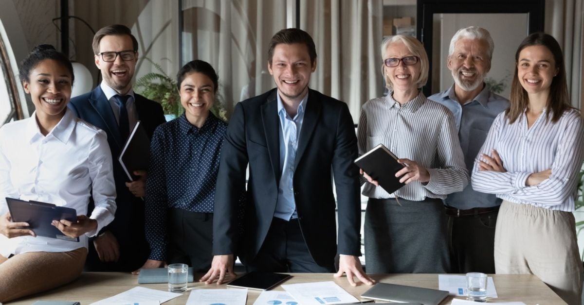 Group of professionals and executives gathered around a table with reports