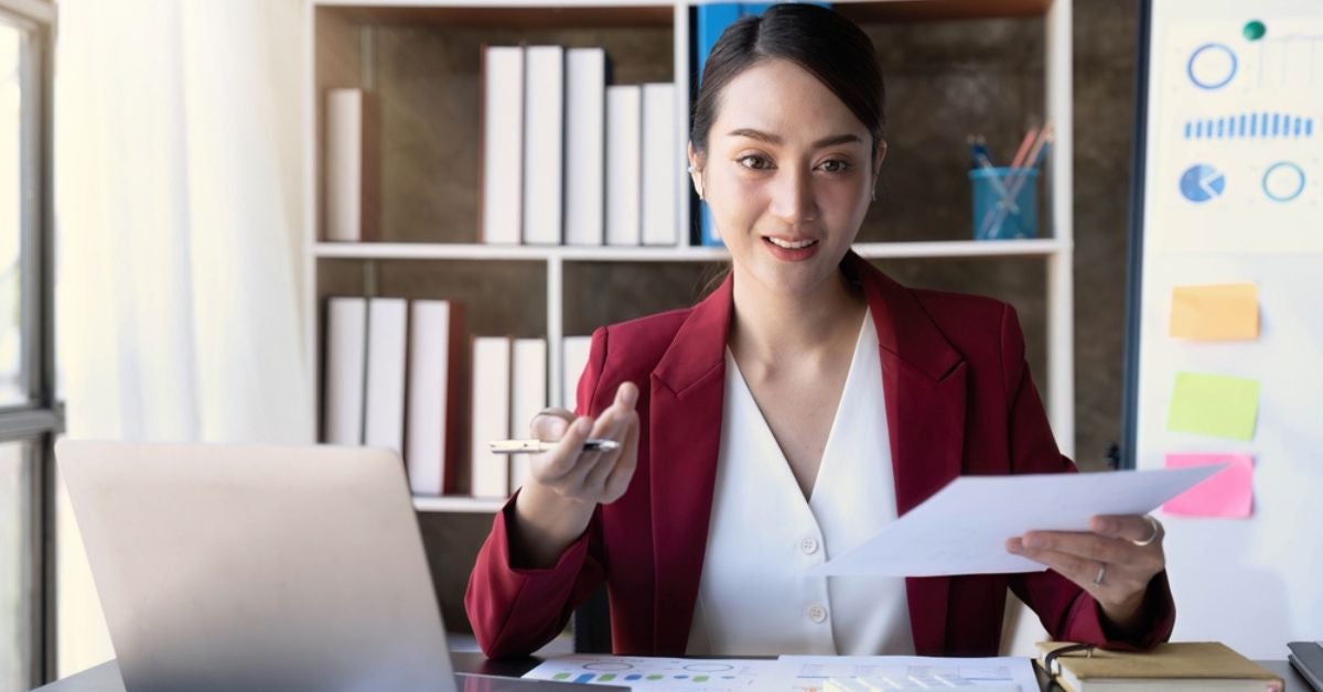 Professional woman sitting behind a desk holding a report