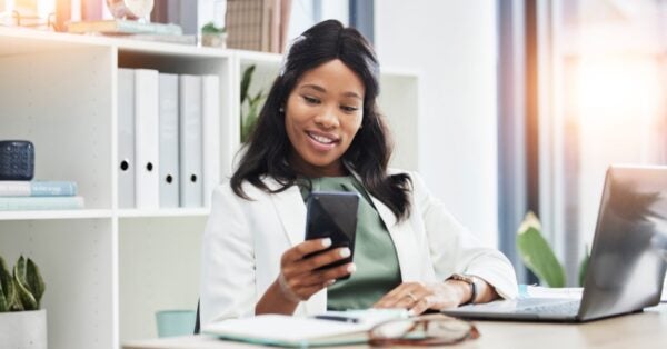 Happy Female Professional at Desk Looking at Smart Phone