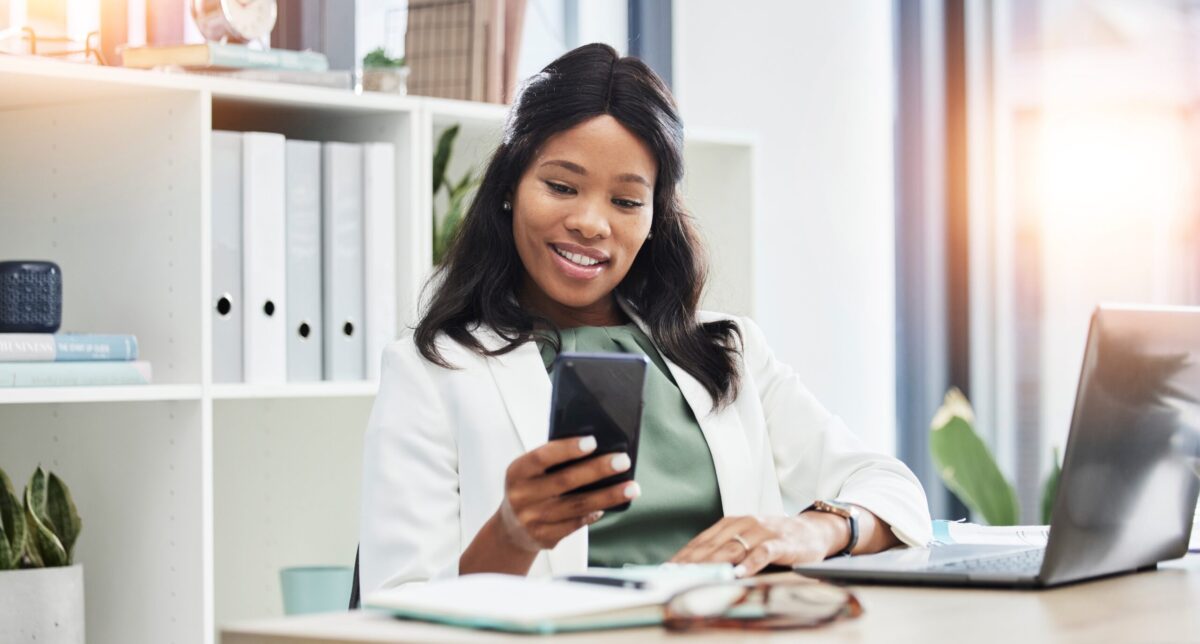Happy Female Professional at Desk Looking at Smart Phone