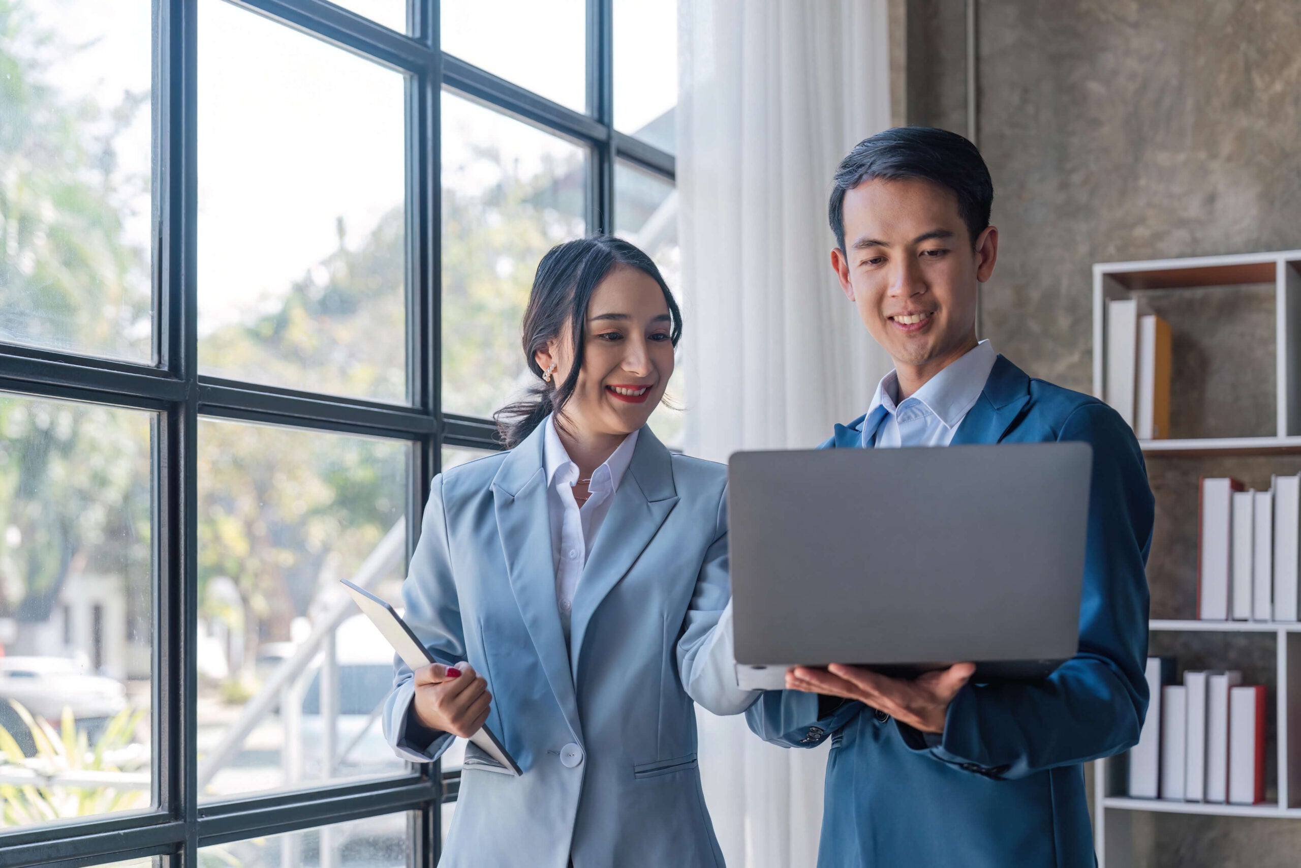 business professionals standing holding laptop