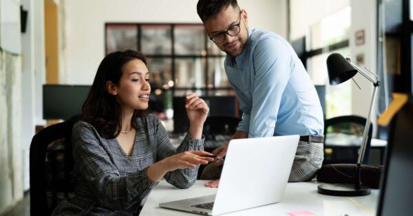 two coworkers chat at desk