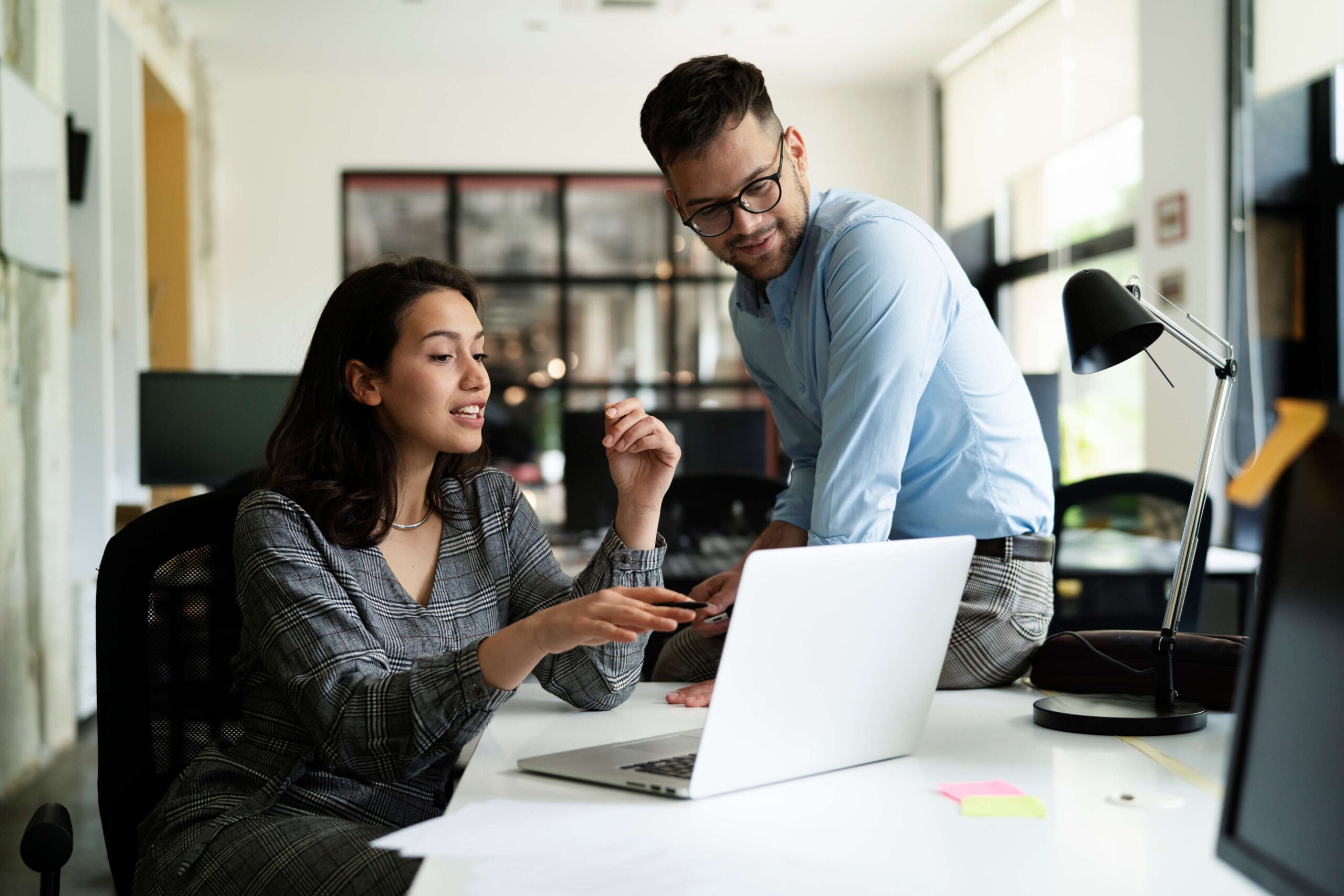 two coworkers chat at desk