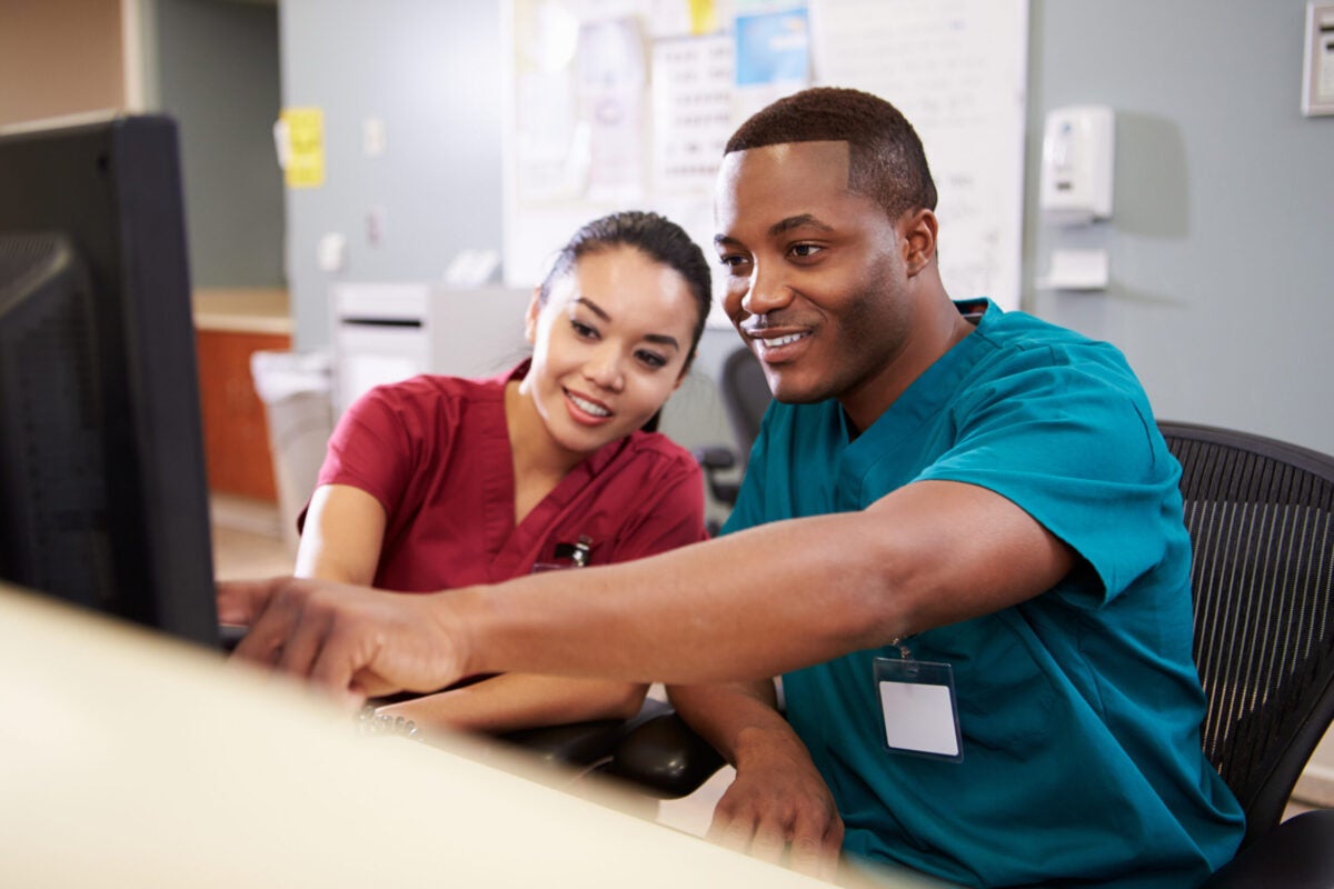 Two healthcare practitioners pointing to information on a computer