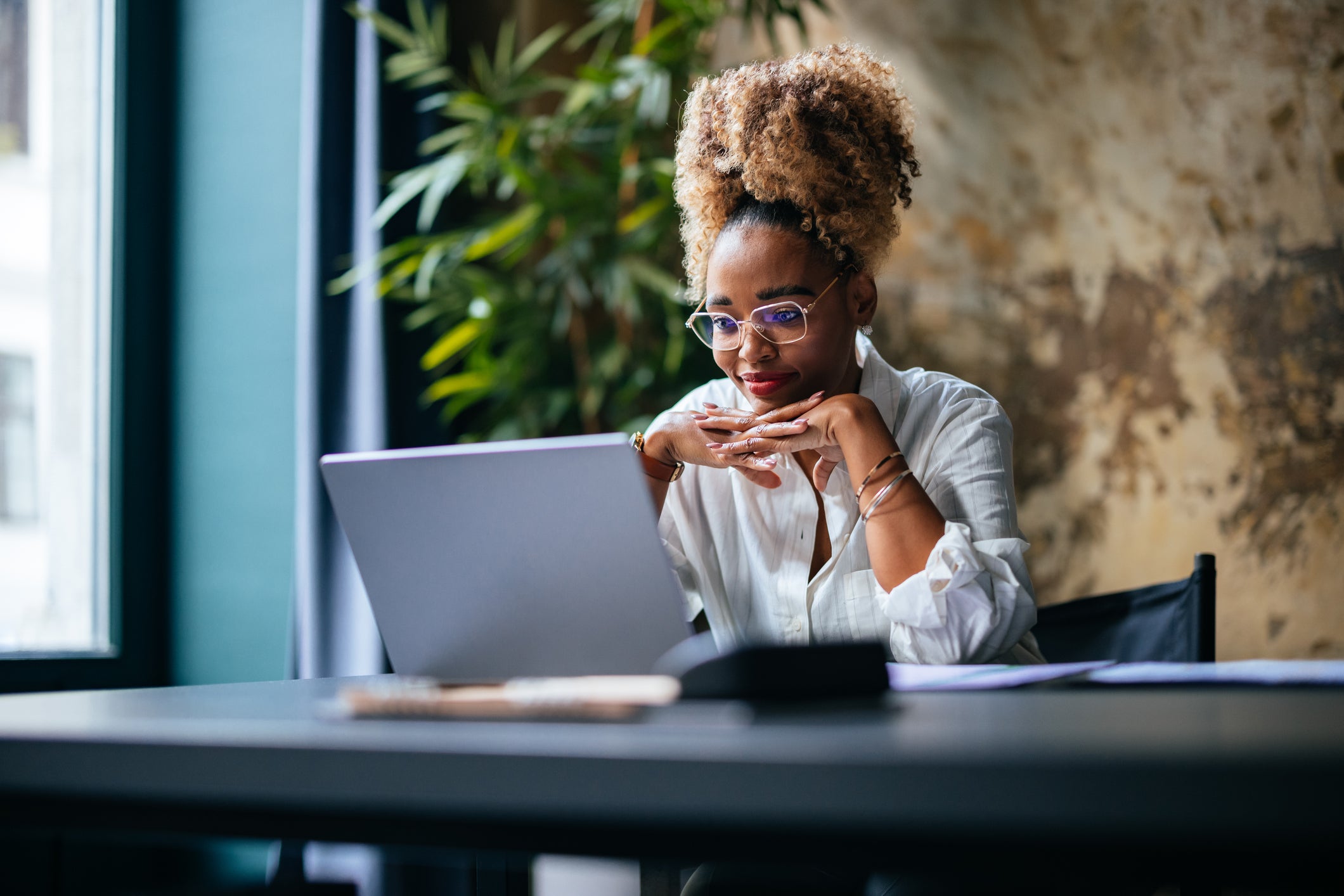 A female talent acquisition professional is sitting in front of her computer and smiling.